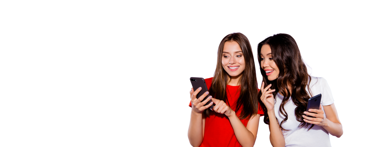 Zwei Frauen stehen lächelnd nebeneinander und schauen auf ihr Handy