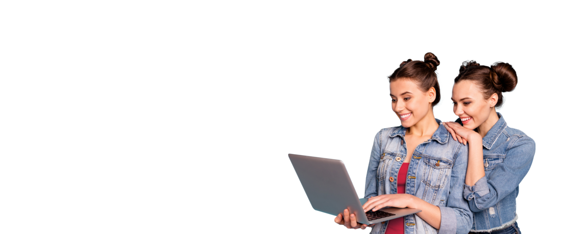 Zwei Frauen lächeln während sie auf den Laptop schauen.