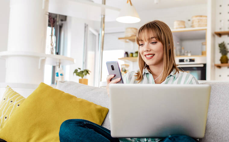 Das Bild zeigt eine Frau mit Laptop und Smartphone